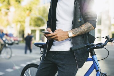 Teenager mit Fixie-Fahrrad, der ein Smartphone benutzt - EBSF001743
