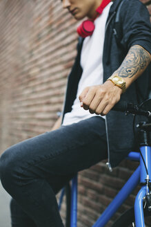 Teenager mit Fixie-Fahrrad, goldener Uhr und Tattoo auf dem Unterarm - EBSF001748