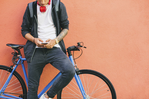 Teenager mit Fixie-Fahrrad, der ein Smartphone benutzt, lizenzfreies Stockfoto