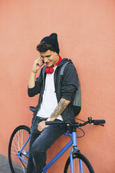 Teenager mit Fixie-Fahrrad, der ein Smartphone benutzt - EBSF001760