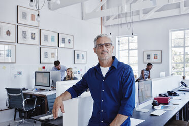 Portrait of confident businessman in office with staff in background - RORF00286