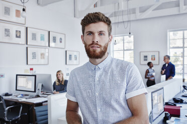 Businessman in office with staff in background - RORF00288