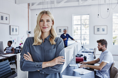 Portrait of confident businesswoman in office with staff in background - RORF00289