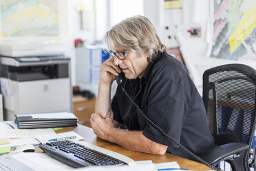 Älterer Mann telefoniert am Schreibtisch in seinem Büro - TCF05102