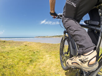 Frankreich, Bretagne, Mann auf elektrischem Mountainbike an der Küste - LAF01716