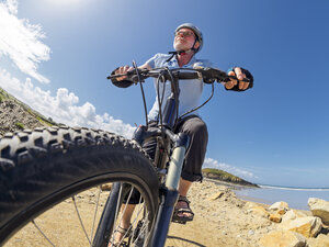 France, Brittany, senior man on electric mountainbike on coastal trail - LAF01717