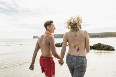 Teenage couple walking on the beach - UUF08411