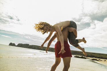 Playful teenage couple on the beach - UUF08413