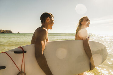 Teenage couple carrying surfboard at the sea - UUF08434