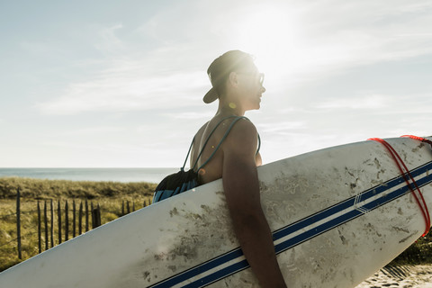 Junger Mann mit Surfbrett an der Küste, lizenzfreies Stockfoto