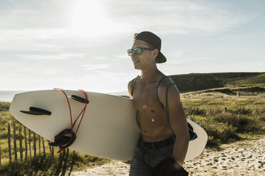 Junger Mann mit Surfbrett an der Küste - UUF08451