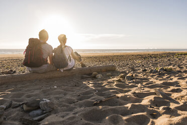 Frankreich, Bretagne, Finistere, Halbinsel Crozon, Paar bei Strandspaziergang, am Strand sitzend, Sonnenuntergang genießend - UUF08467