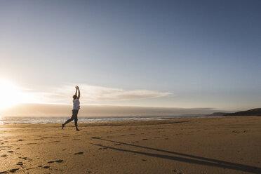 France, Bretagne, Crozon peninsula, woman jumping on beach at sunset - UUF08477