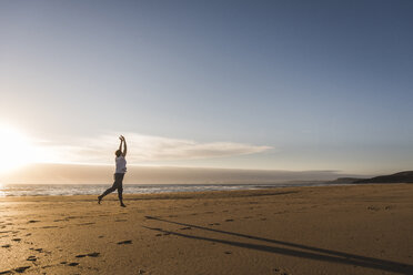 Frankreich, Bretagne, Halbinsel Crozon, Frau springt bei Sonnenuntergang am Strand - UUF08477