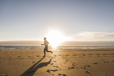 France, Bretagne, Crozon peninsula, woman running on beach at sunset - UUF08478