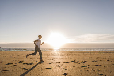 Frankreich, Bretagne, Halbinsel Crozon, Frau läuft bei Sonnenuntergang am Strand - UUF08479