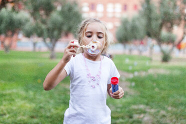 Little girl blowing soap bubbles in a park - VABF00773