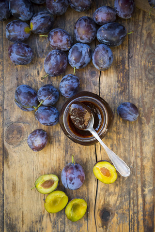 Preserving jar of plum jam and plums on wood stock photo