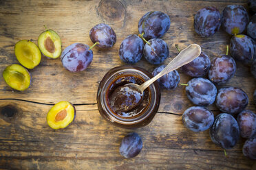 Preserving jar of plum jam and plums on wood - LVF05294