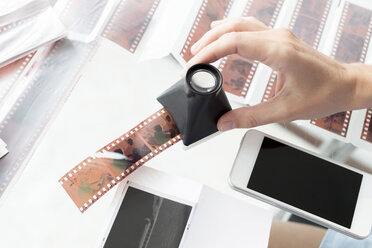 Woman checking film strips with magnifying glass - KNTF00484
