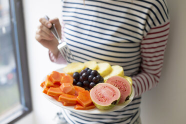 Woman holding plate with fresh fruit - KNTF00488