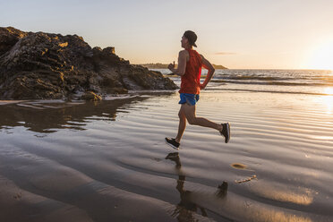 Frankreich, Halbinsel Crozon, Jogger am Strand bei Sonnenuntergang - UUF08488