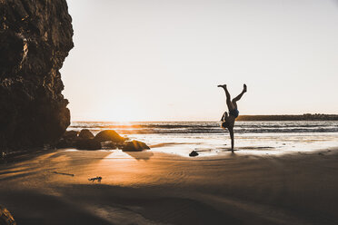 France, crozon peninsula, young man doing handstand on one arm at sunset - UUF08499