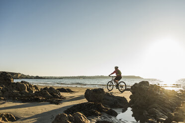 France, Crozon peninsula, Man biking on the beach - UUF08503