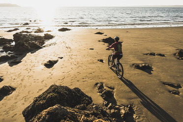 France, Crozon peninsula, Man biking on the beach - UUF08504