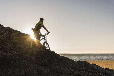 Frankreich, Halbinsel Crozon, Mountainbiker mit Blick auf den Sonnenuntergang - UUF08512