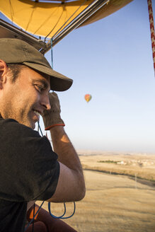 Lächelnder Heißluftballonpilot beim Betrachten der Landschaft - ABZF01225