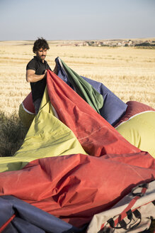 Mann beim Verpacken einer Heißluftballonhülle - ABZF01239