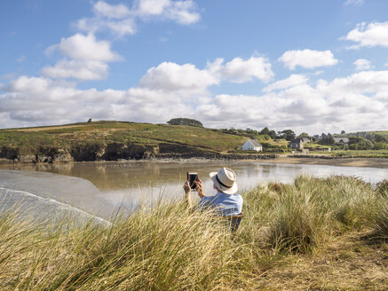 Frankreich, Bretagne, Sainte-Anne-la-Palud, älterer Mann mit Tablet am Strand Treguer plage - LAF01721