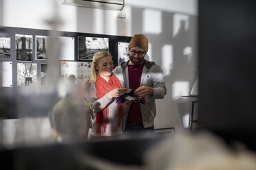 Junges Paar steht in der Bibliothek eines Designerbüros - ZEF10343