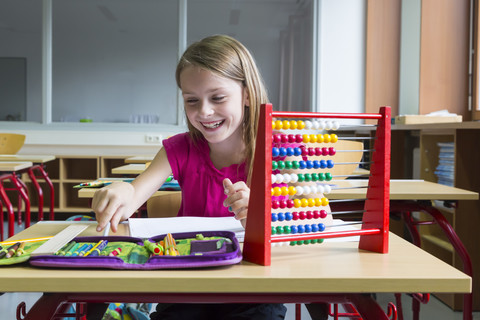 Smiling schoolgirl sitting at desk in her class stock photo
