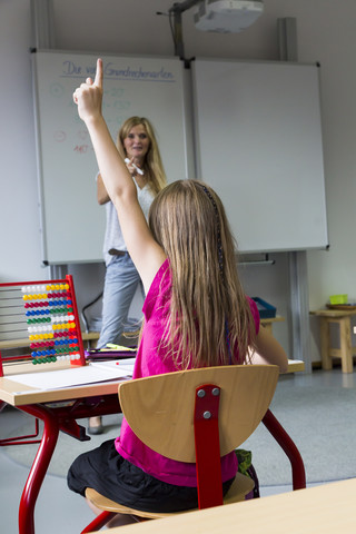 Back view of schoolgirl raising her hand stock photo