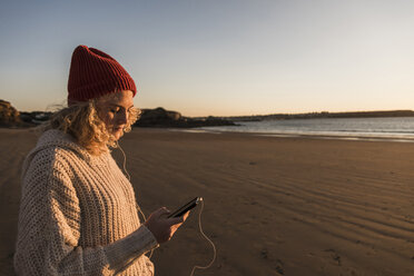 Teenager-Mädchen am Strand mit Smartphone - UUF08544