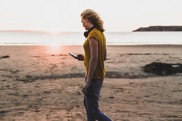 Teenager-Mädchen am Strand mit Smartphone - UUF08559