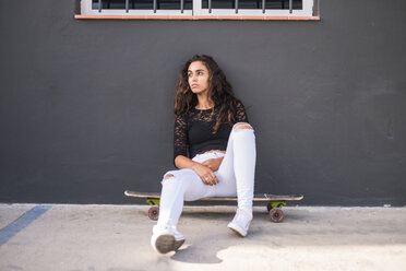 Teenager-Mädchen sitzt auf einem Skateboard - SIPF00839