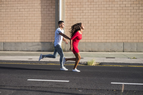 Teenagerpaar läuft Hand in Hand auf einer Straße, lizenzfreies Stockfoto