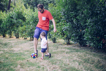Vater spielt Fußball mit seinem kleinen Sohn auf einer Wiese - JPSF00008
