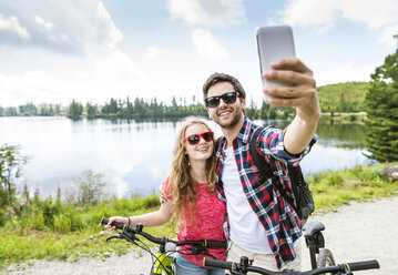 Young couple taking selfies on a bicycle trip - HAPF00856