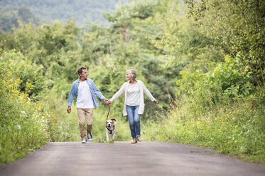 Älteres Paar auf einem Spaziergang mit Hund in der Natur - HAPF00880