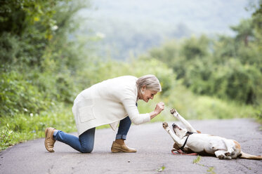 Ältere Frau mit ihrem Hund in der Natur - HAPF00885