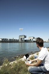 Mature man sitting in grass flying a drone - ONF01009