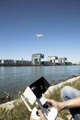 Mature man sitting in grass flying a drone - ONF01013