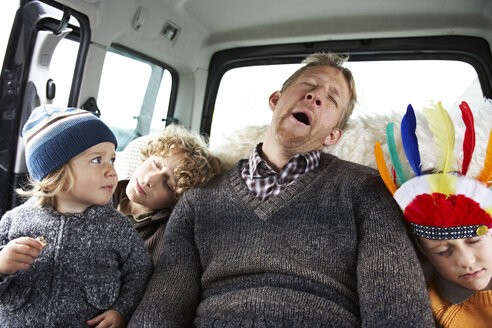 Sleeping father sitting in car on back seat with his sons - FSF00453
