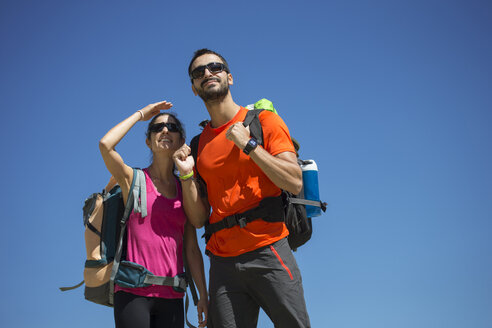 Hiking couple looking out under blue sky - ERLF00187