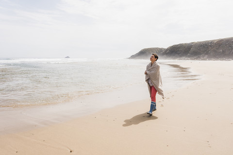 Ältere Frau geht am Strand spazieren, lizenzfreies Stockfoto