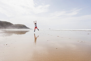 Reife Frau springt am Strand - UUF08568